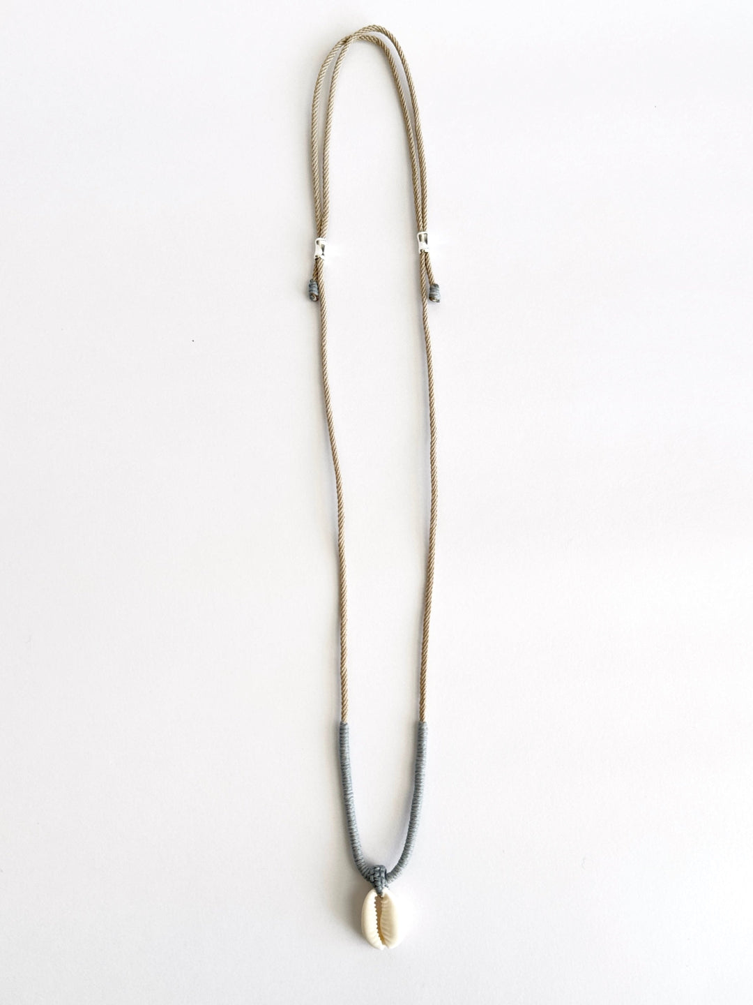 Cove Necklace: Natural Cowrie shell pendant with handcrafted macrame wrapping in smoky pastel tones by Lala Fshasha.