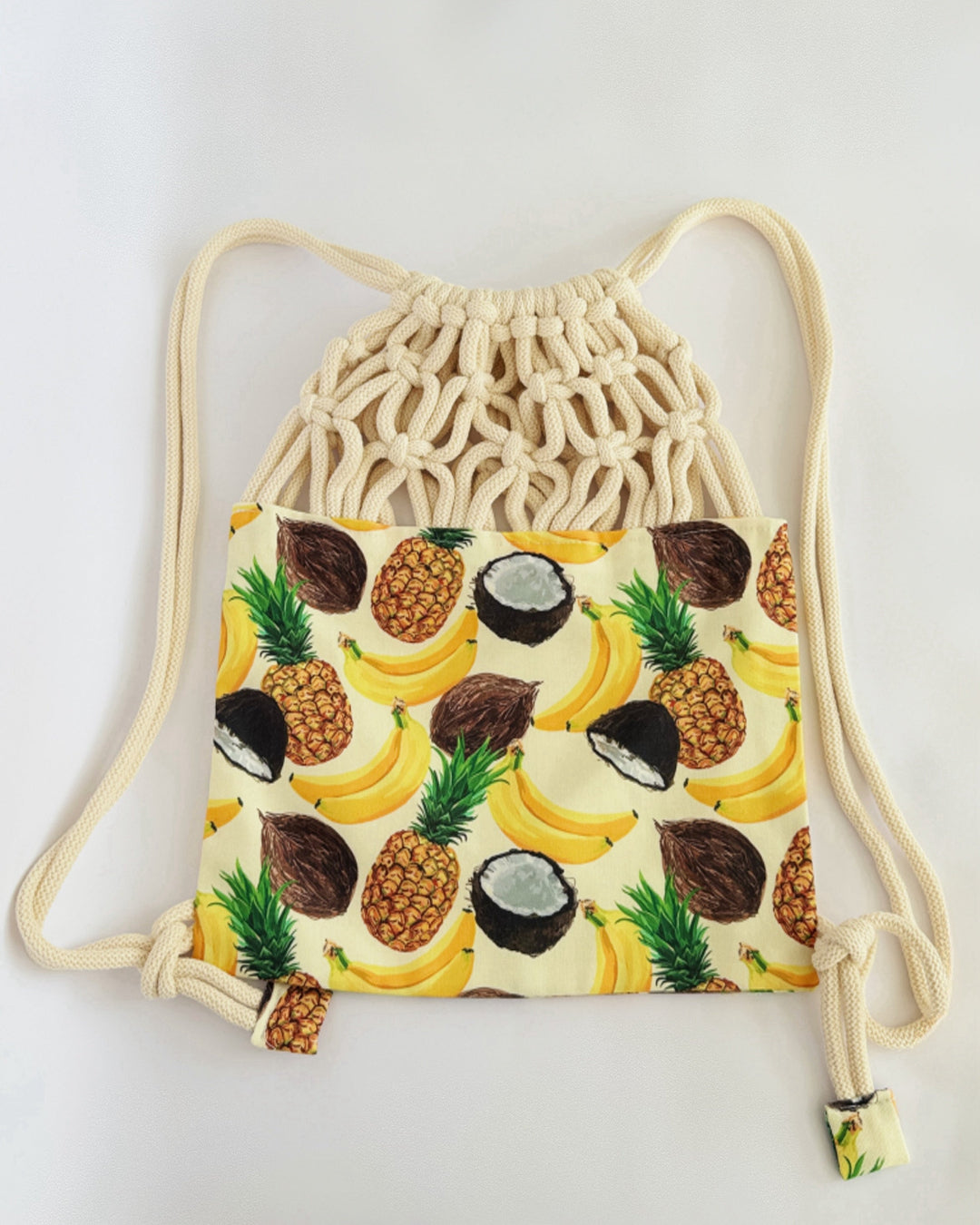 Handmade macramé backpack with soft cream macramé top and tropical fruit print canvas bottom in beige tones – Tropica Zanzibar design.