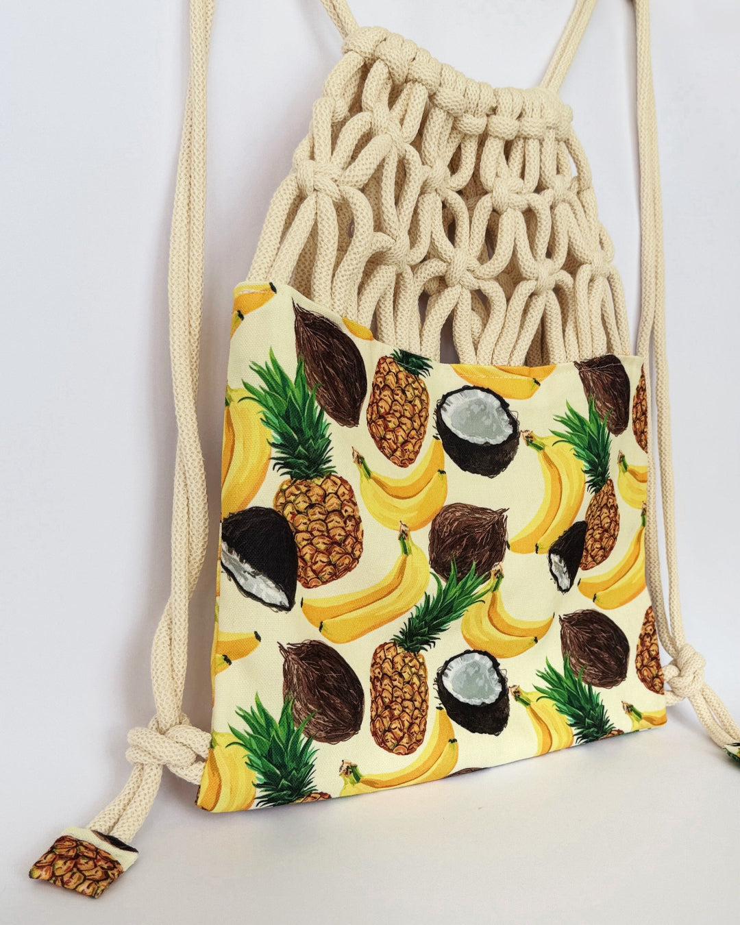 Handmade macramé backpack with soft cream macramé top and tropical fruit print canvas bottom in beige tones – Tropica Zanzibar design. SIDE