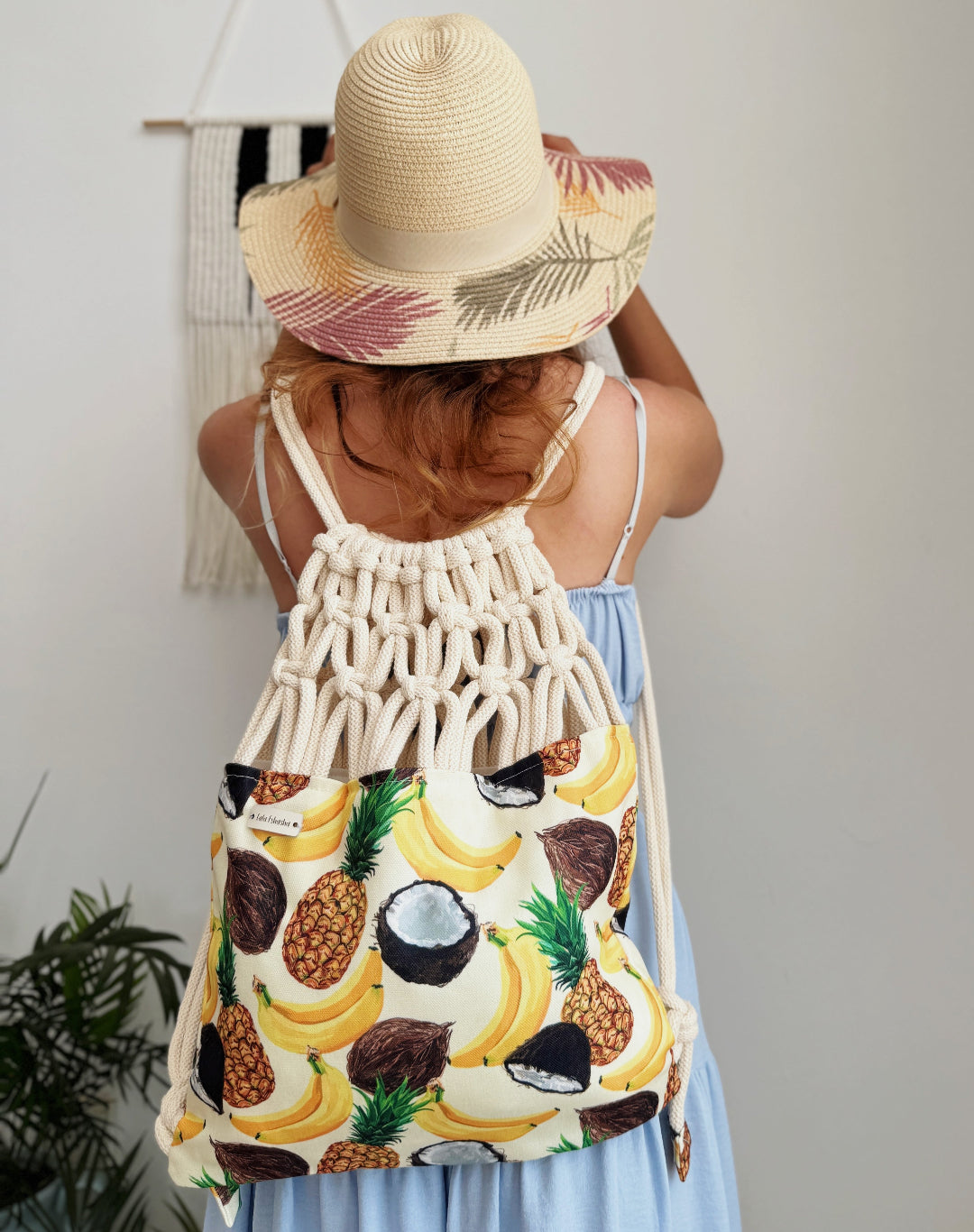 Handmade macramé backpack with soft cream macramé top and tropical fruit print canvas bottom in beige tones – Tropica Zanzibar design. on a model.