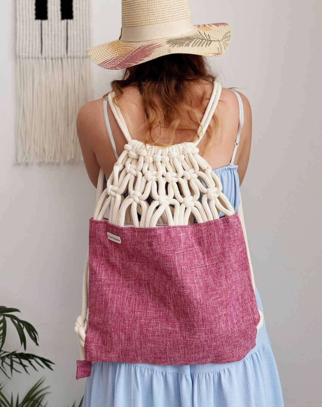 Handmade macramé backpack with soft cream macramé top and rose-merlot canvas-style bottom – Tropica Merlot design, textured and elegantly natural. on a model.