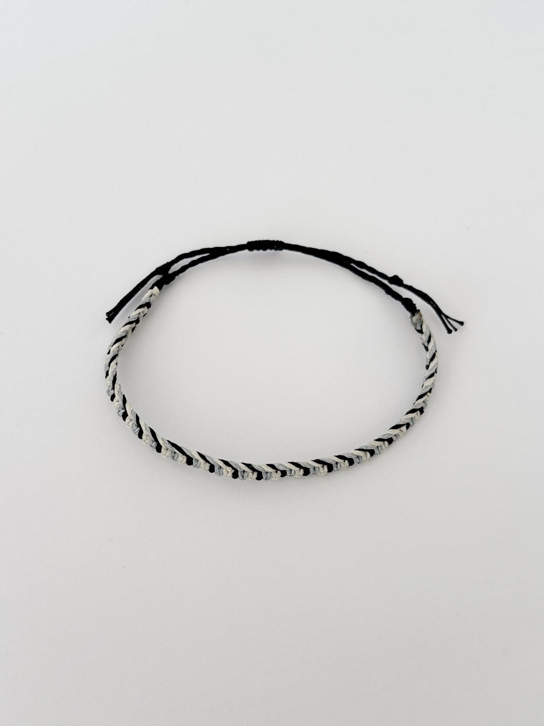 צמיד Tide מקרמה לגבר בעבודת יד על רקע בהיר, בגווני שחור ותכלת-אפרפר.