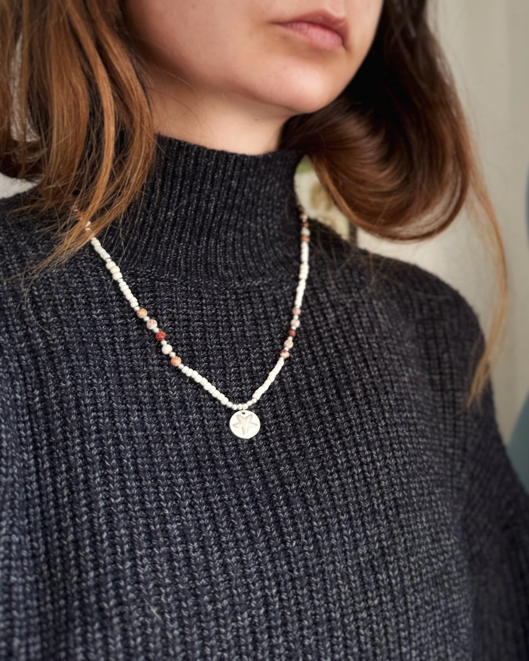 שרשרת Mirage היא שרשרת חרוזים עדינה בעבודת יד, בגוונים חמים של לבן, קרם ואדמדם. 