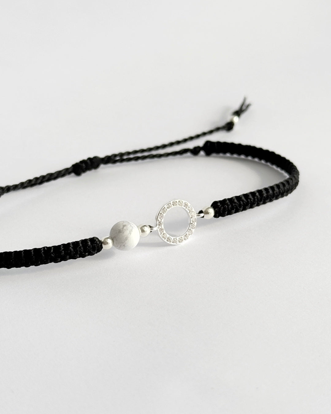 צמיד מקרמה עדין מדגם Halo, עם אלמנט עגול מצופה זרקונים ואבן Howlite לבנה, מצולם על רקע נקי