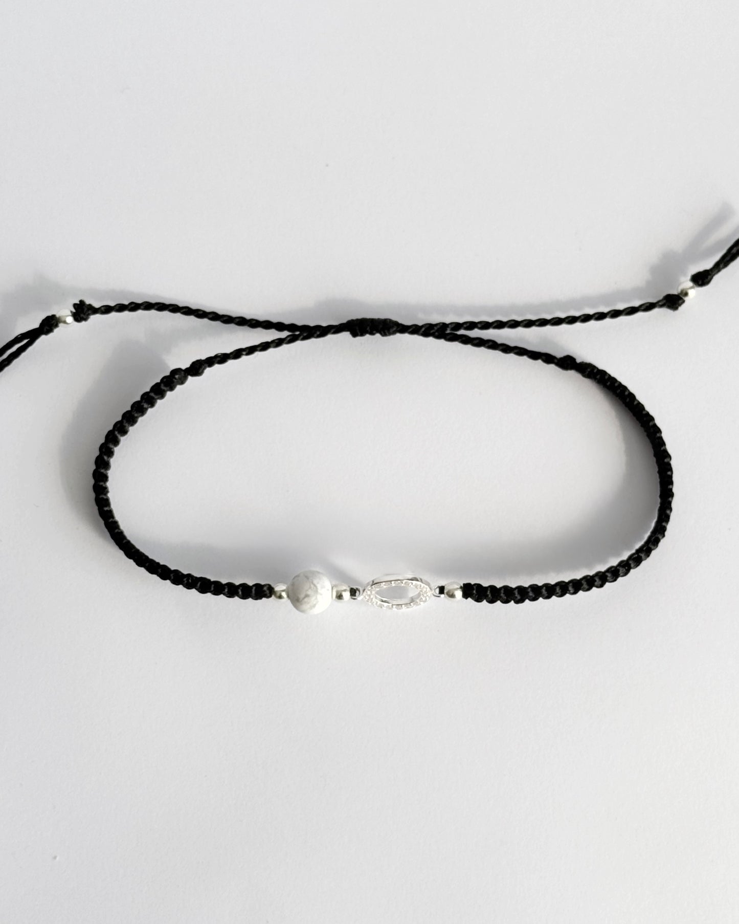 צמיד מקרמה עדין מדגם Halo, עם אלמנט עגול מצופה זרקונים ואבן Howlite לבנה, מצולם על רקע נקי