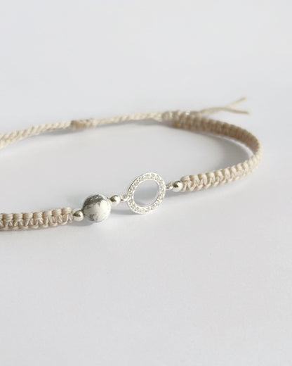 צמיד מקרמה עדין מדגם Halo, עם אלמנט עגול מצופה זרקונים ואבן Howlite לבנה, מצולם על רקע נקי