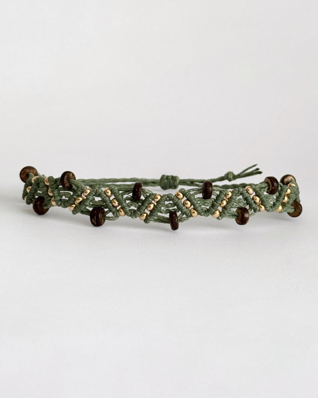 צמיד מקרמה Grove בירוק זית עם חרוזי עץ כהים וחרוזים מוזהבים, מצולם על רקע נקי.