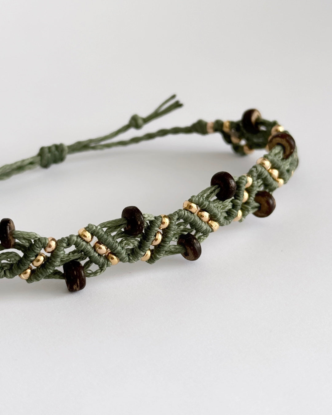 צמיד מקרמה Grove בירוק זית עם חרוזי עץ כהים וחרוזים מוזהבים, מצולם על רקע נקי.