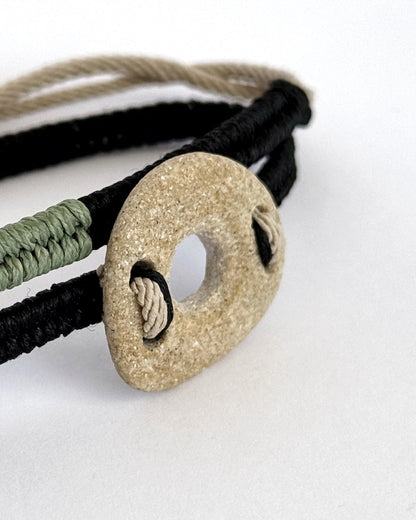 Close-up of light natural pebble in handmade macramé bracelet with exposed knot detail