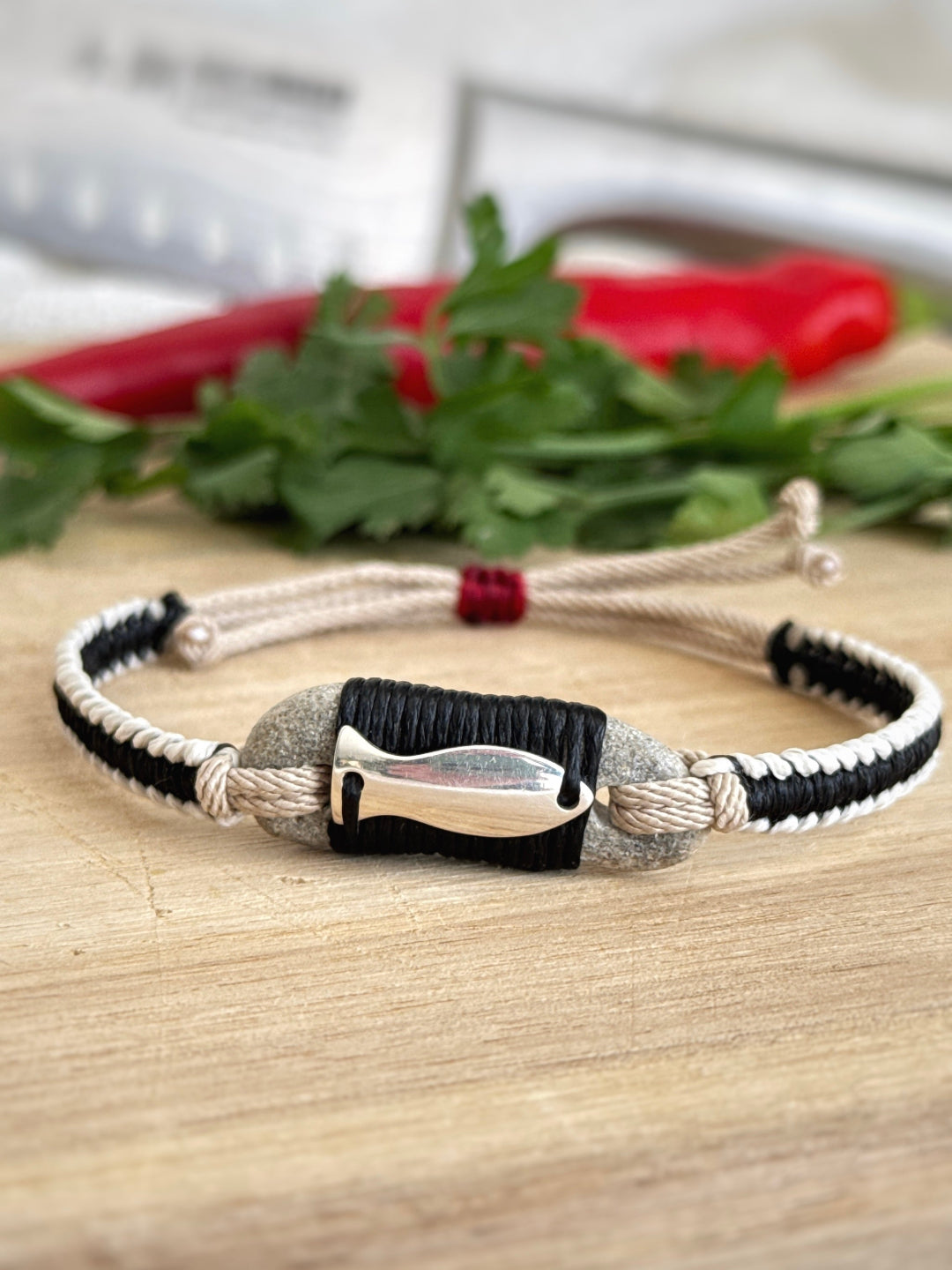 Handmade macramé bracelet with natural pebble stone and silver fish charm, material-focused design