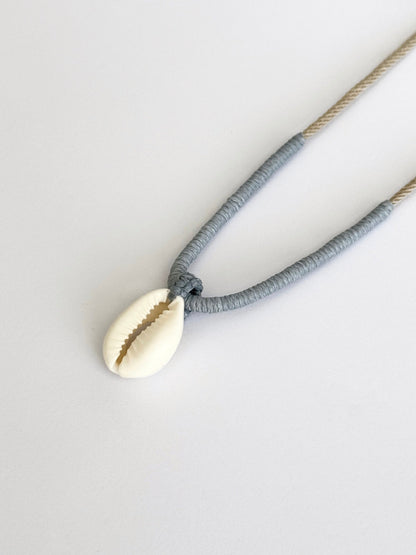 Cove Necklace: Natural Cowrie shell pendant with handcrafted macrame wrapping in smoky pastel tones by Lala Fshasha.